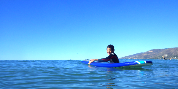 Alec learning how to surf with the help of a new friend